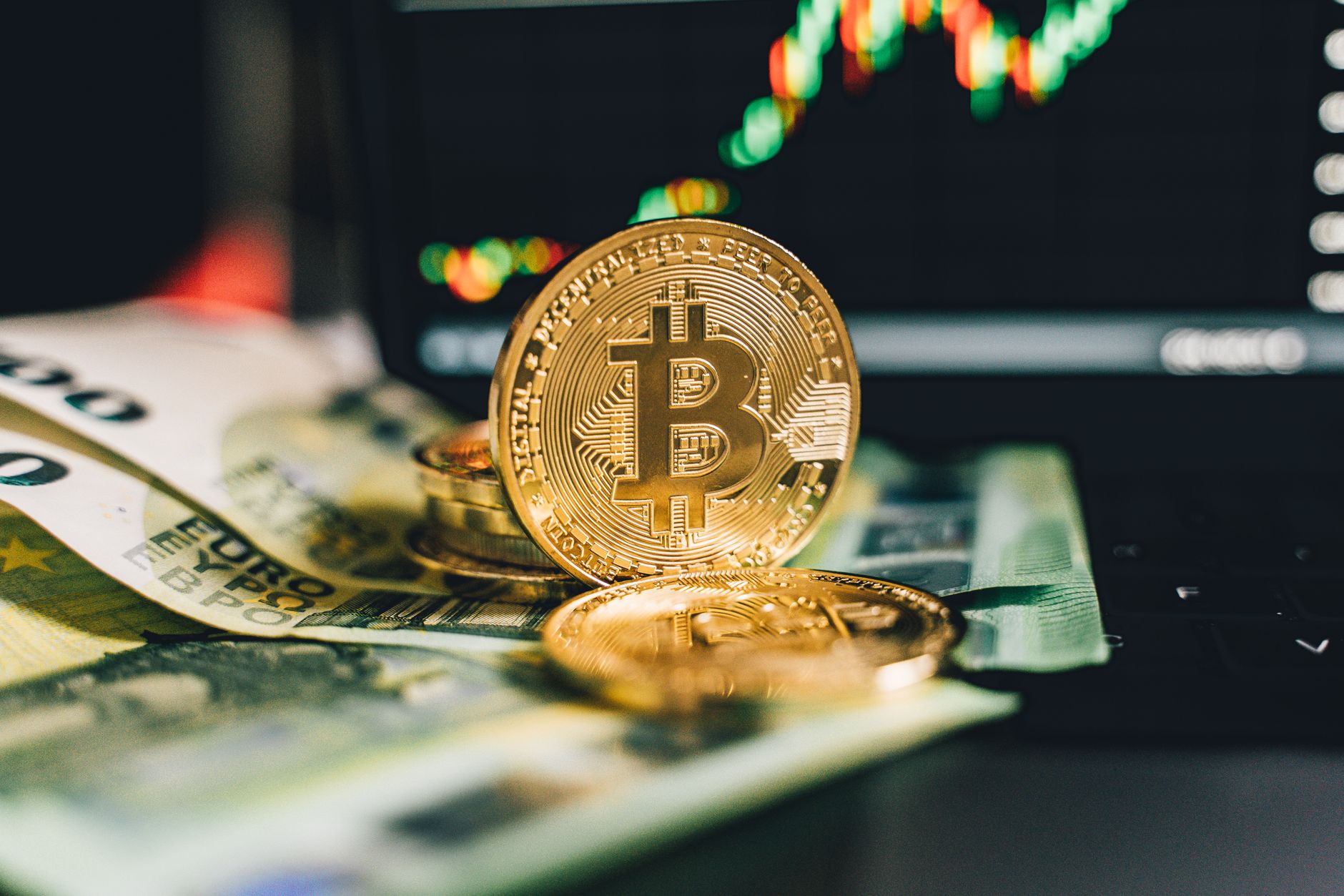 Visualizing the trends in crypto mining profitability. Close-up of Bitcoin and Euro notes on laptop keyboard with market chart in background.