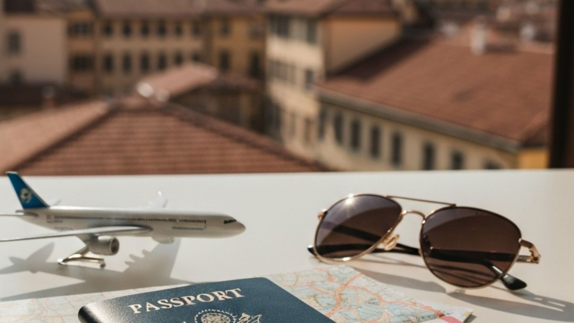 A U.S. passport resting on a folded map and boarding pass with a European city skyline in the background