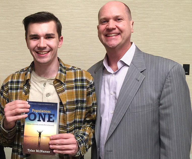 Tyler McNamer holding his book Population ONE, next to his dad, Jody