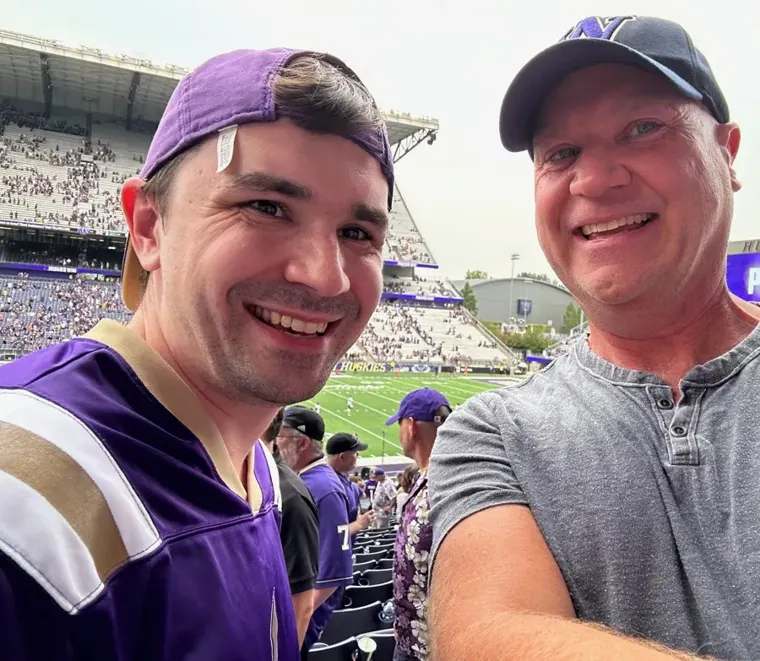 Tyler McNamer and his dad Jody smiling together at a football game