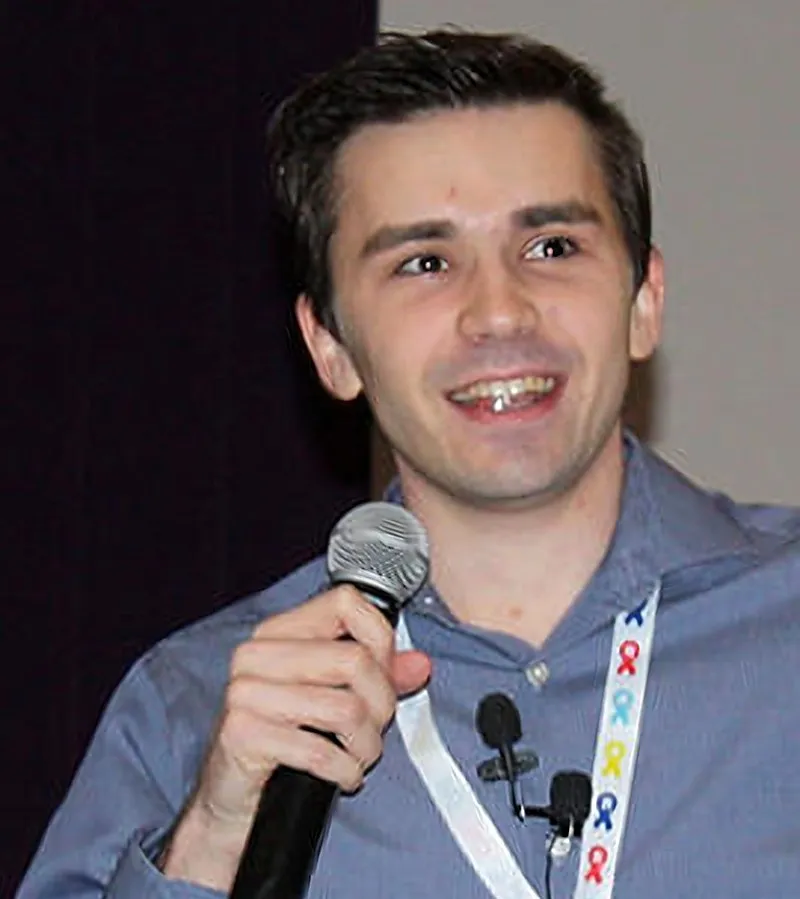 Tyler McNamer speaking on stage with a microphone